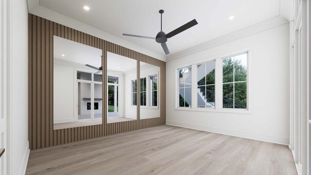 an empty room with wooden floor ceiling fan and windows
