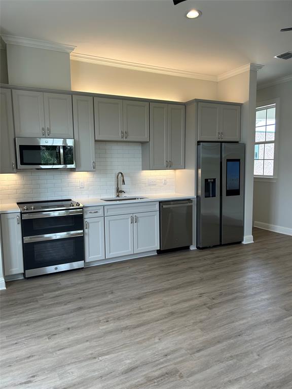 1946 Chestnut Pk Lane Shreveport, LA 71106 - Photo 16 of 23 Kitchen featuring crown molding, stainless steel appliances, tasteful backsplash, gray cabinets, and light countertops