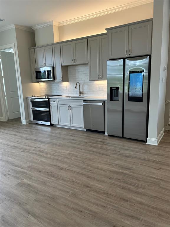 1946 Chestnut Pk Lane Shreveport, LA 71106 - Photo 18 of 23 Kitchen with ornamental molding, appliances with stainless steel finishes, gray cabinetry, wood finished floors, and tasteful backsplash
