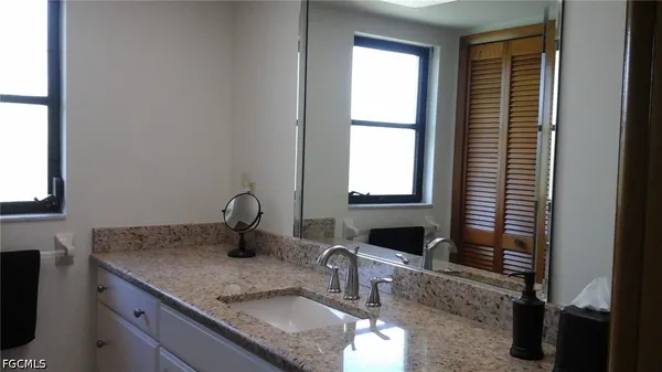 a bathroom with a granite countertop sink and a window