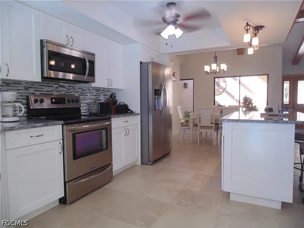 a kitchen with stainless steel appliances granite countertop a stove top oven a refrigerator a sink a dining table and chairs