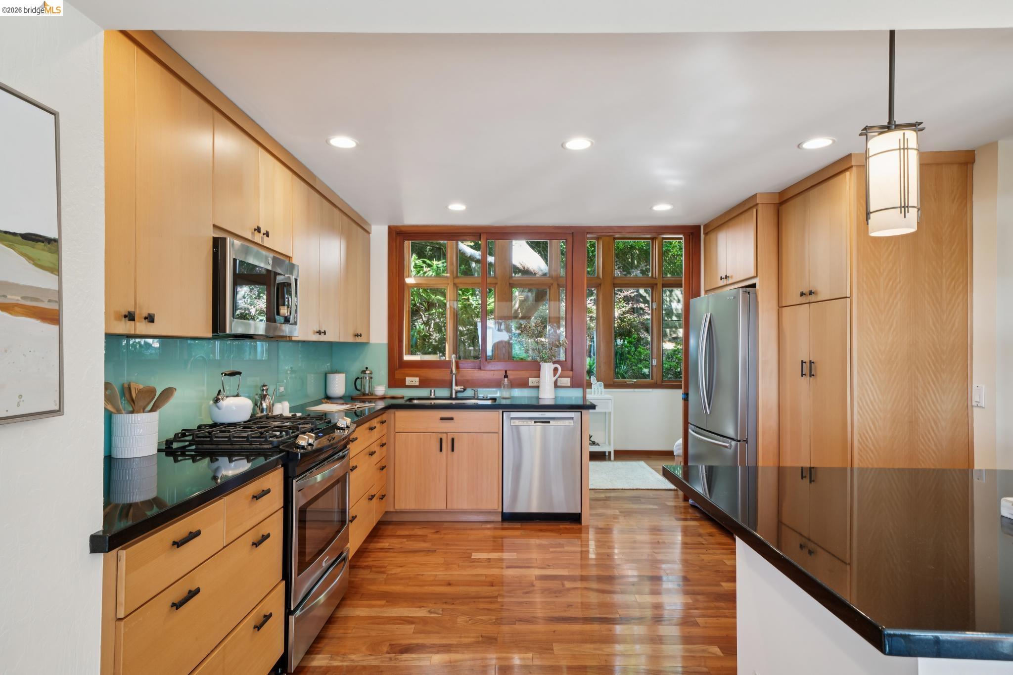 1183 Keeler Avenue Berkeley, CA 94708 - Photo 21 of 53 Kitchen featuring light wood finish cabinetry, stainless steel appliances, light wood finished floors, decorative light fixtures, and decorative backsplash