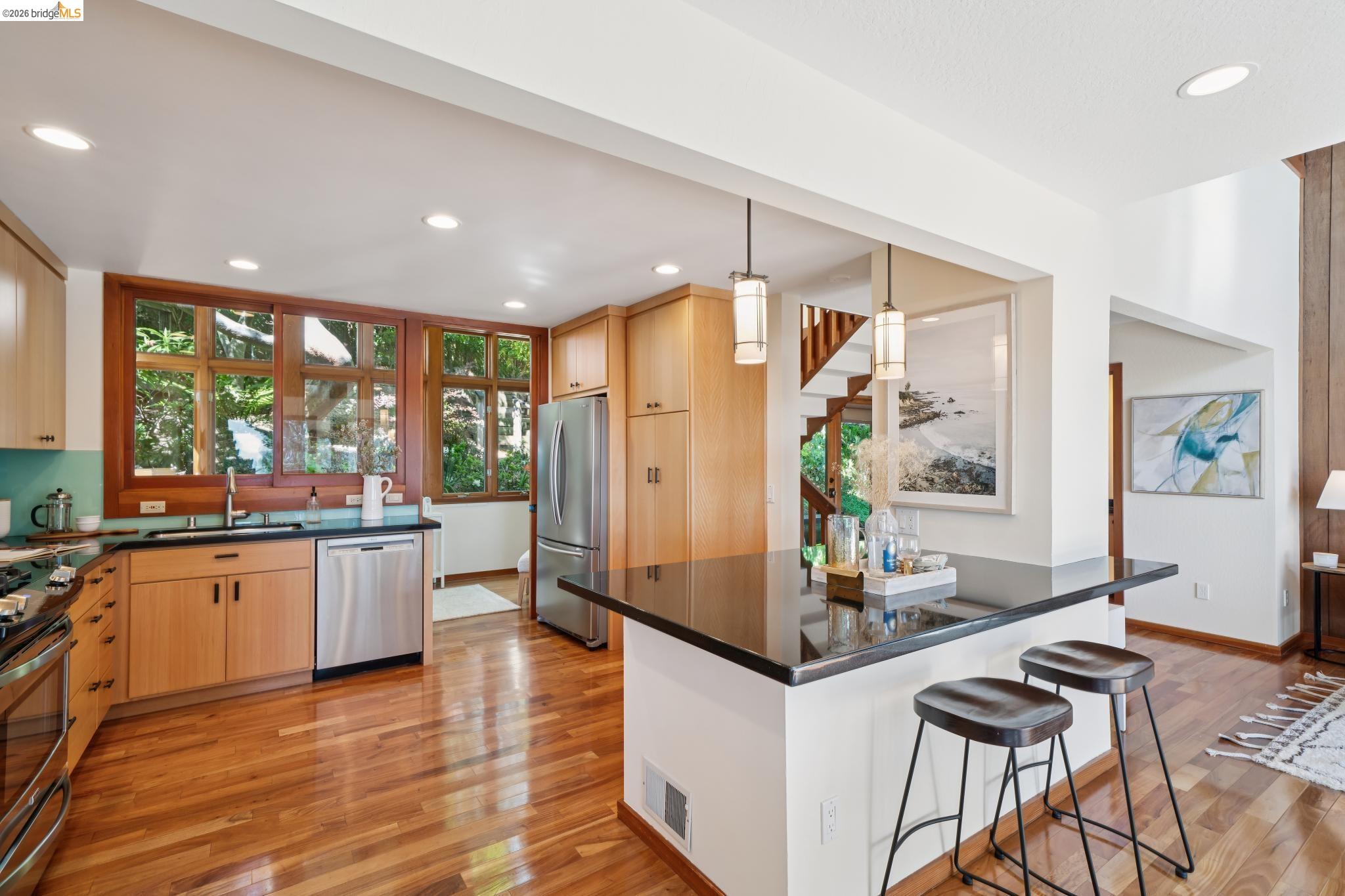 1183 Keeler Avenue Berkeley, CA 94708 - Photo 22 of 53 Kitchen featuring light wood finish cabinetry, decorative light fixtures, a breakfast bar, and stainless steel appliances