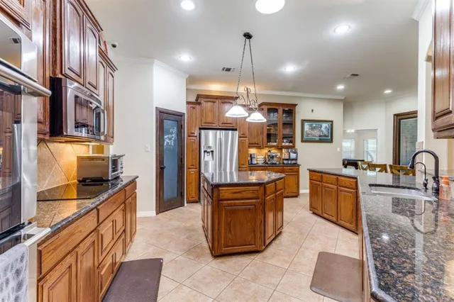 a kitchen with stainless steel appliances granite countertop a sink a stove and a refrigerator