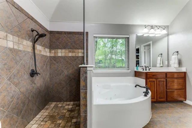 a bathroom with a tub a sink a mirror and a shower