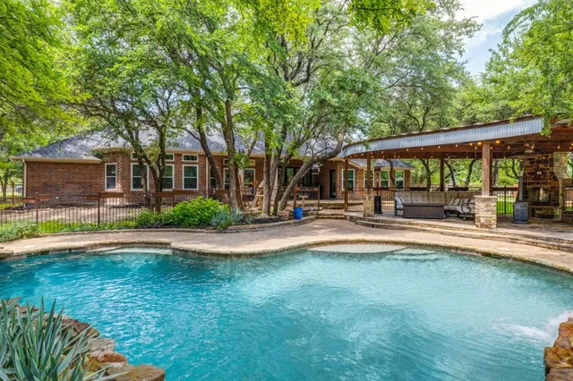 a view of swimming pool with outdoor seating and trees in the background