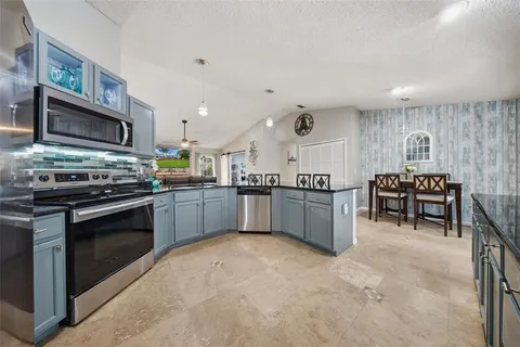 a kitchen with stainless steel appliances a stove a sink a microwave a dining table and chairs