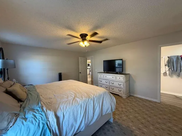 a bedroom with a bed a chandelier and a flat screen tv