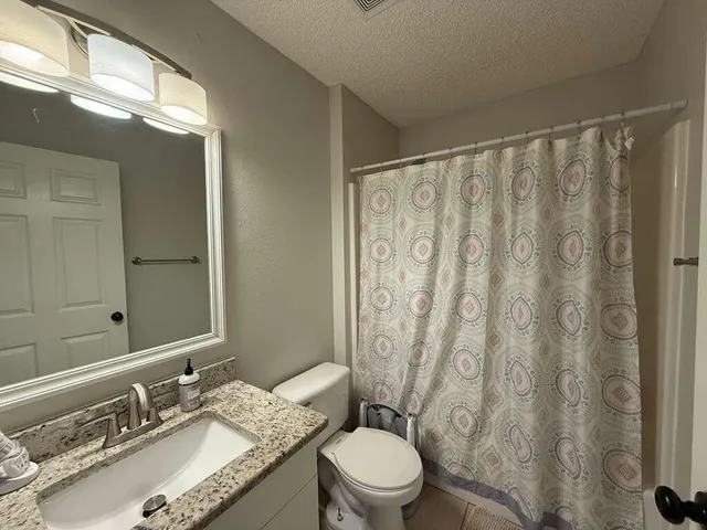 a bathroom with a granite countertop sink toilet and shower