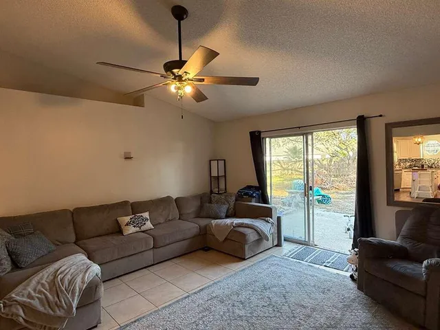 a living room with furniture a ceiling fan and a large window