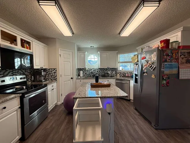 a kitchen with stainless steel appliances granite countertop a refrigerator stove and wooden floor