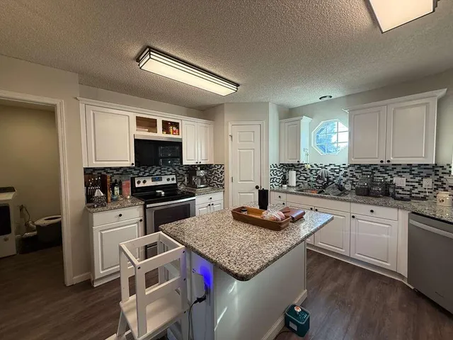 a kitchen with granite countertop stainless steel appliances a stove sink microwave and cabinets