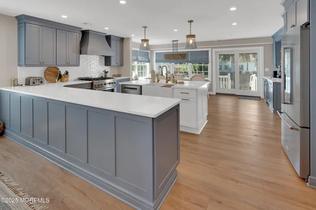 a kitchen with stainless steel appliances granite countertop a refrigerator a sink dishwasher a oven and white cabinets with wooden floor