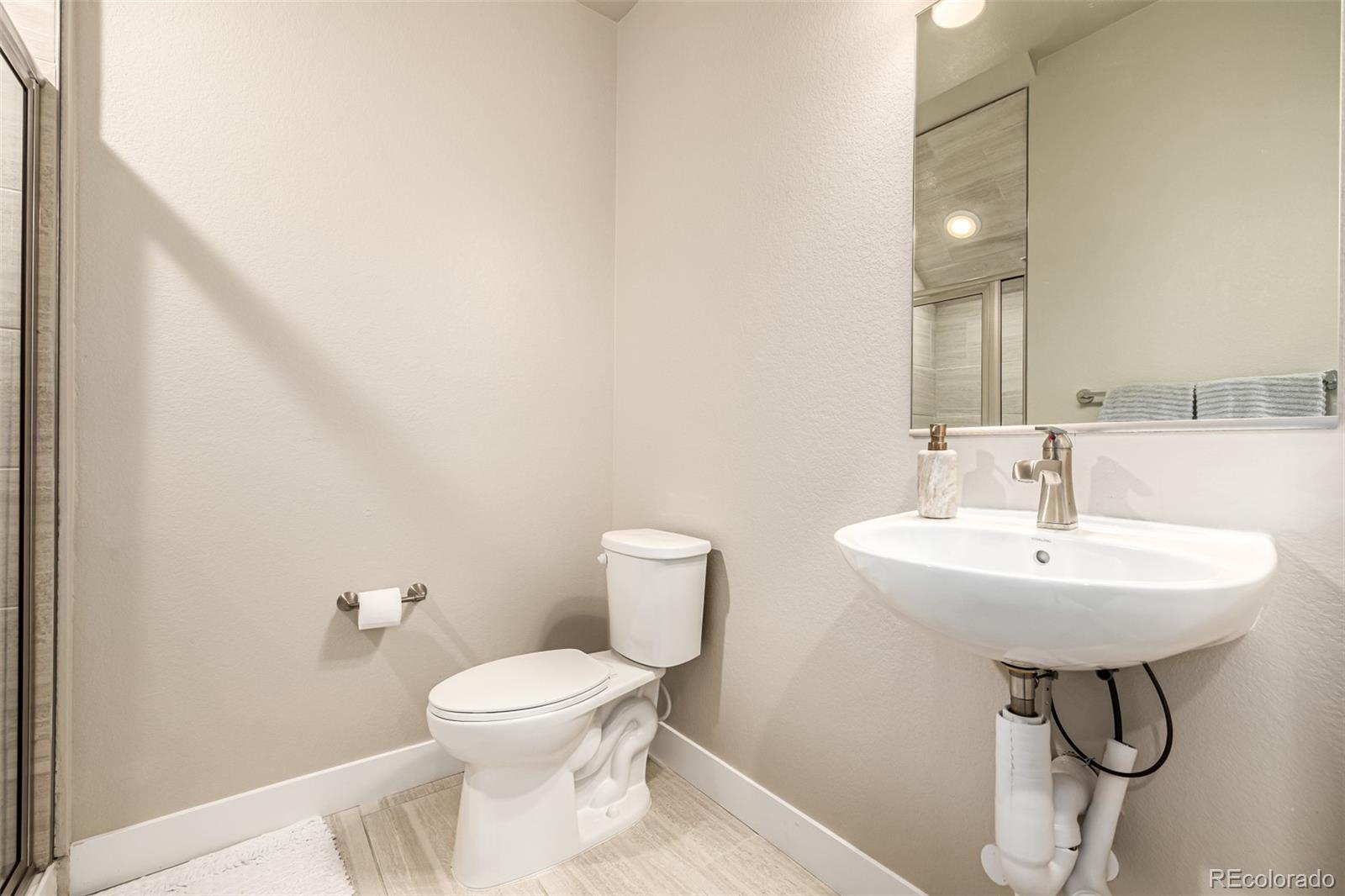 1575 West 68th Avenue Denver, CO 80221 - Photo 21 of 39 a bathroom with a toilet a sink and mirror