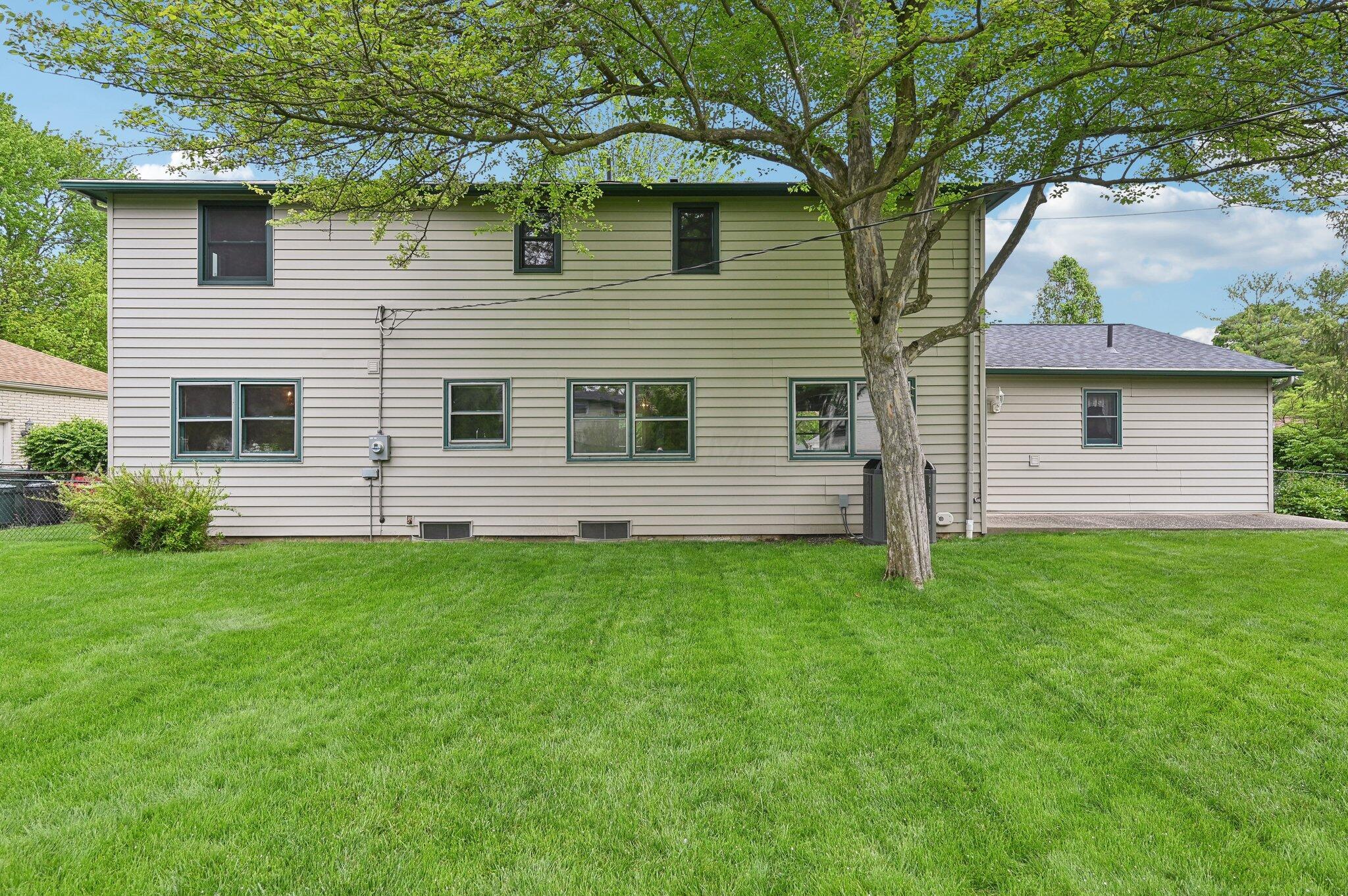 5917 Rocky Rill Road Columbus, OH 43235 - Photo 41 of 47 Rear Exterior View
Spacious and neatly manicured backyard showcasing the full rear elevation of the home. Vinyl siding, multiple windows for natural light, and an updated HVAC unit are visible. A large shade tree adds character to the outdoor space.