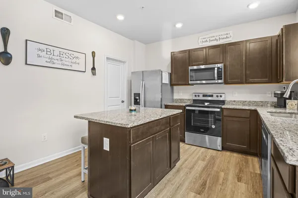 a kitchen with kitchen island granite countertop stainless steel appliances and wooden cabinets