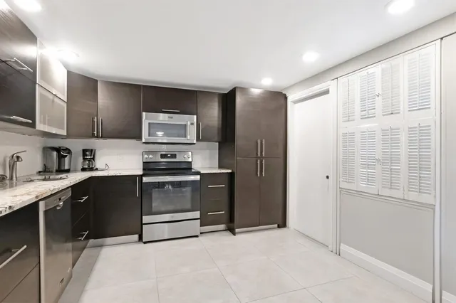 a kitchen with granite countertop a refrigerator and a stove top oven