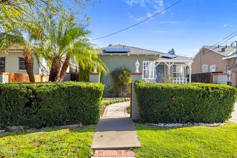 a front view of a house with a yard and potted plants