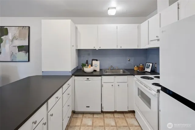 a kitchen with granite countertop white cabinets and white appliances