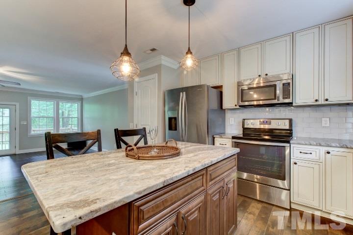 521 Ranch Farm Road Raleigh, NC 27603 - Photo 12 of 30 a kitchen with stainless steel appliances granite countertop wooden cabinets a stove a kitchen island with chairs and wooden floor