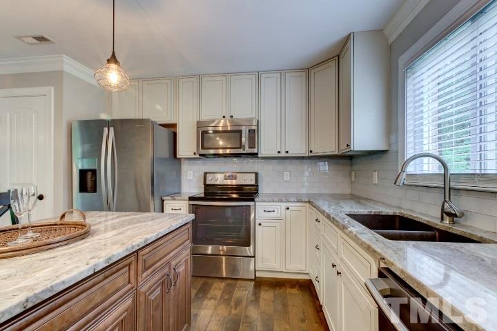 521 Ranch Farm Road Raleigh, NC 27603 - Photo 14 of 30 a kitchen with stainless steel appliances granite countertop a sink a stove a refrigerator cabinets and wooden floor