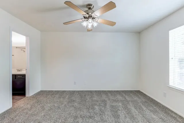 an empty room with windows and fan