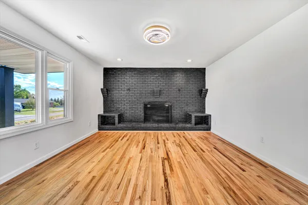 a view of empty room with wooden floor and fireplace