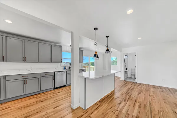 a large kitchen with stainless steel appliances refrigerator wooden floor and a stove top oven
