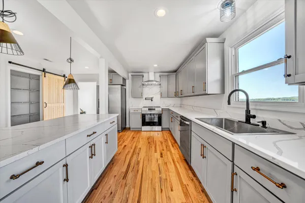 a large kitchen with stainless steel appliances sink a stove and cabinets