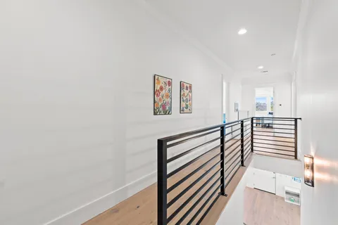 a view of a hallway with wooden floor and stairs