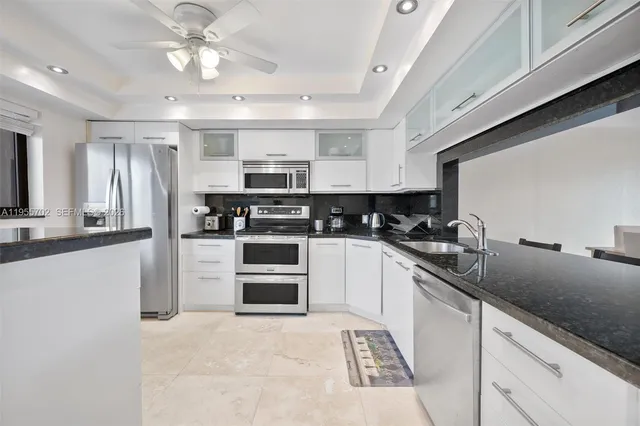 a kitchen with kitchen island granite countertop stainless steel appliances cabinets a sink and a counter top space