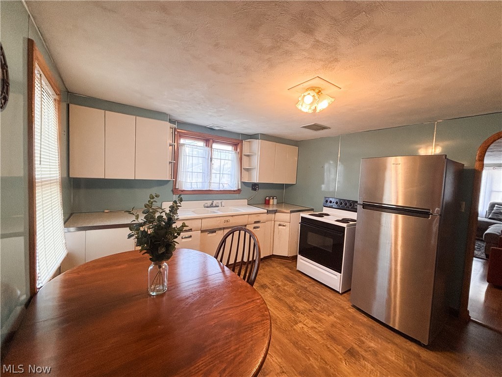 724 East Main Street Barnesville, OH 43713 - Photo 9 of 28 Kitchen featuring freestanding refrigerator, white range with electric cooktop, open shelves, dark wood-style flooring, and a textured ceiling