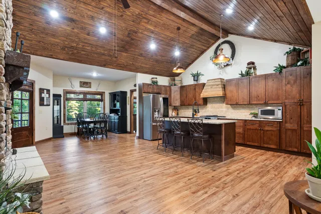 a kitchen with stainless steel appliances a dining table chairs stove refrigerator and cabinets