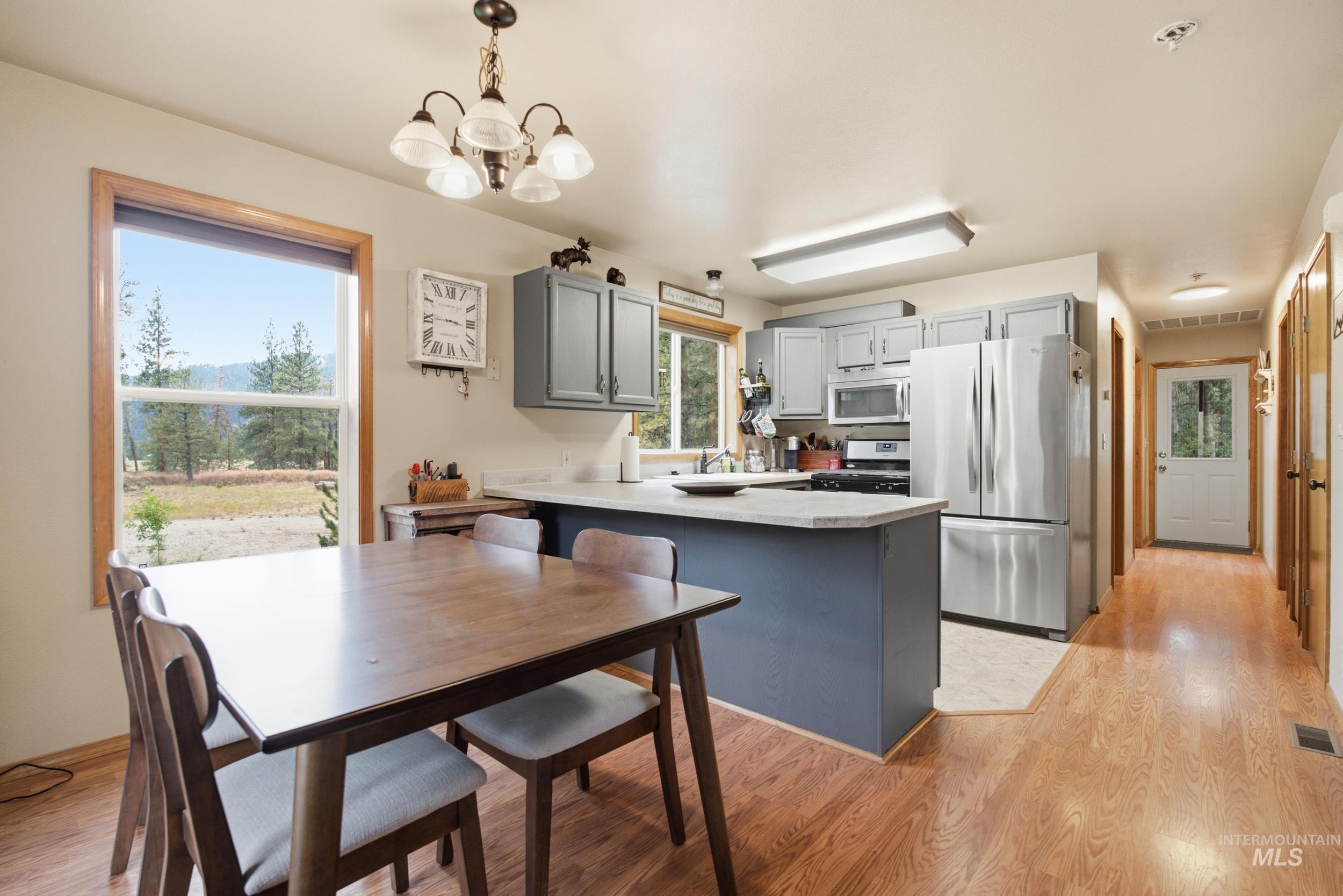 3980 North Pine-Featherville Road Mountain Home, ID 83647 - Photo 13 of 35 Open-concept kitchen and dining area featuring wood-finish flooring, stainless steel appliances, and grey cabinetry