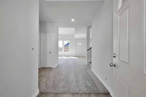 a view of a hallway with wooden floor and a bathroom