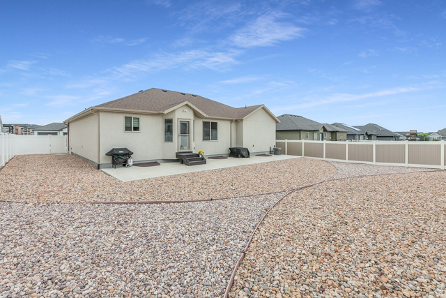1228 North Providence Way Tooele, UT 84074 - Photo 26 of 28 Rear exterior featuring a concrete patio, stucco siding, and a gabled roofline