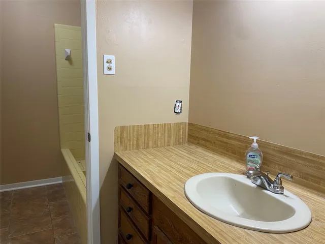 a bathroom with a tub a sink and granite