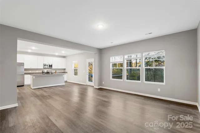 a view of an empty room with window and wooden floor