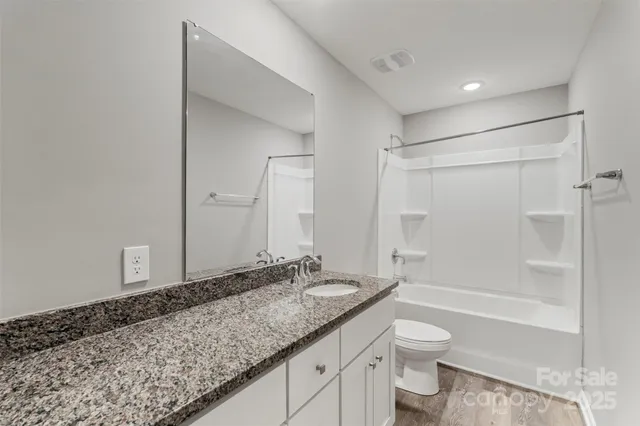a bathroom with a granite countertop sink a toilet and shower