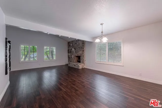 an empty room with wooden floor chandelier and windows