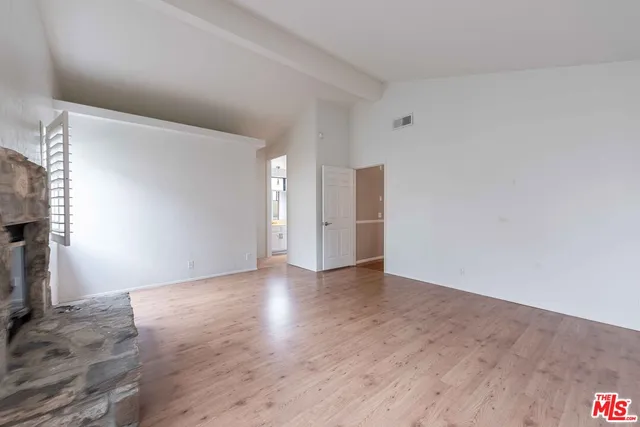 a view of an empty room with wooden floor and a fireplace