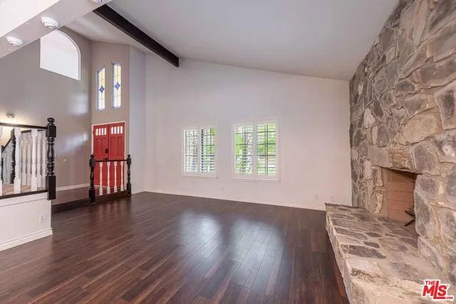 a view of an empty room with wooden floor and a fireplace