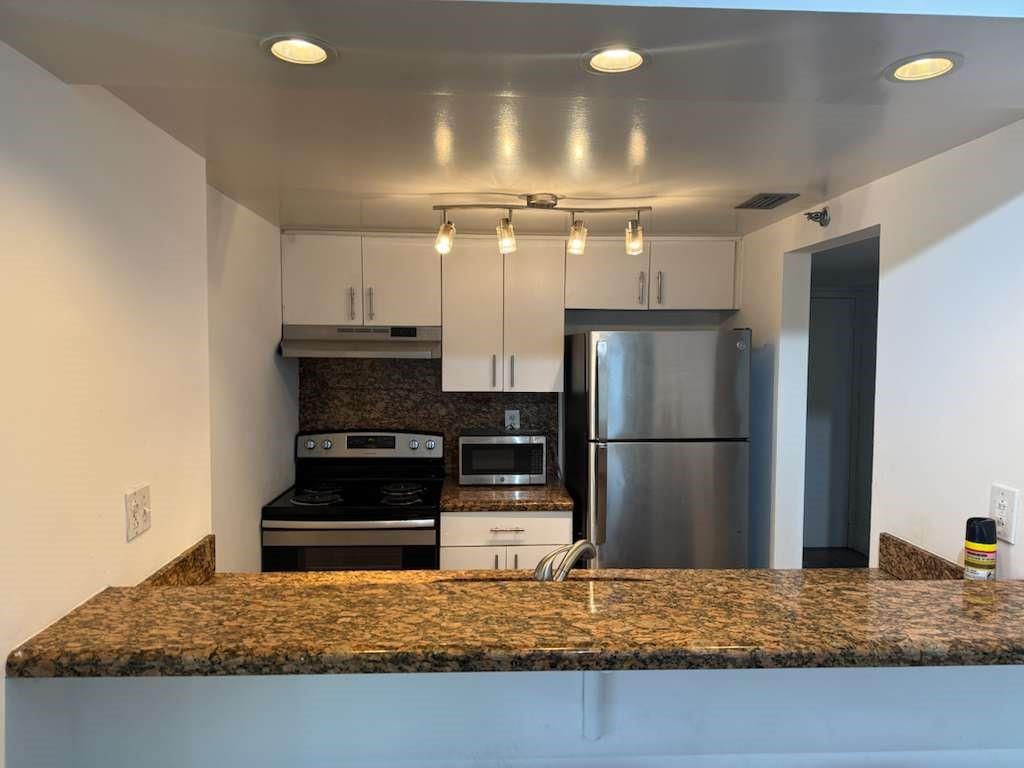 a kitchen with kitchen island granite countertop a refrigerator and a stove