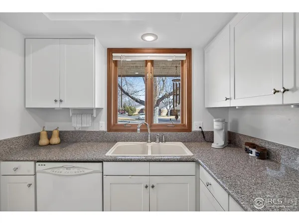 a kitchen with granite countertop a sink window and cabinets