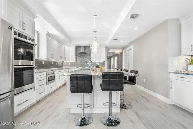 a kitchen with granite countertop a sink stove refrigerator and cabinets