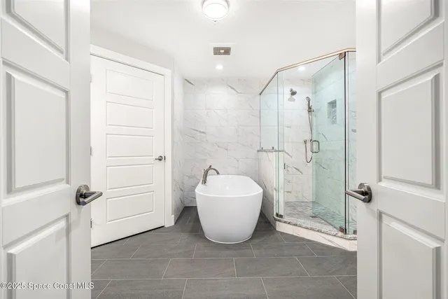 a large bed sitting in a bedroom next to a window and a chandelier