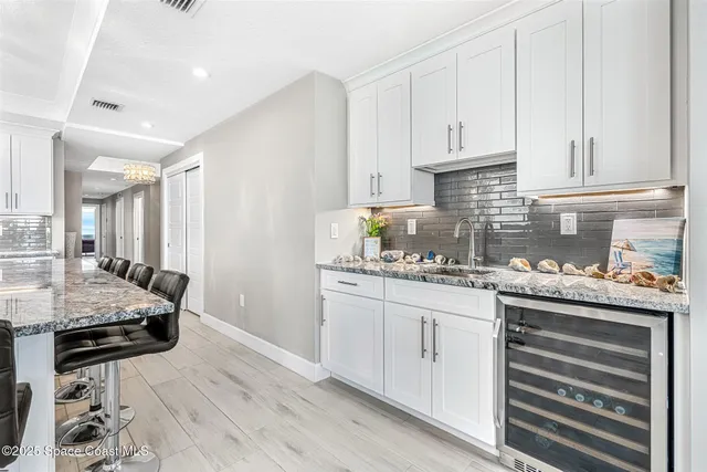 a kitchen with stainless steel appliances kitchen island granite countertop a stove a sink a refrigerator and white cabinets with wooden floor