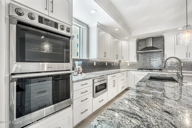 a kitchen with granite countertop a sink stainless steel appliances and cabinets