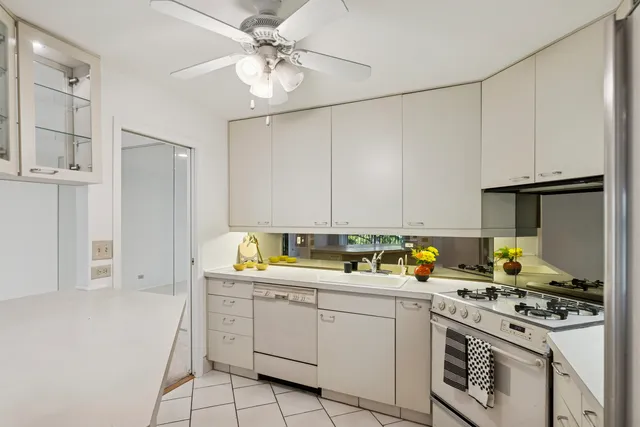 a kitchen with stainless steel appliances a stove a sink and white cabinets