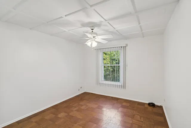 an empty room with windows and ceiling fan